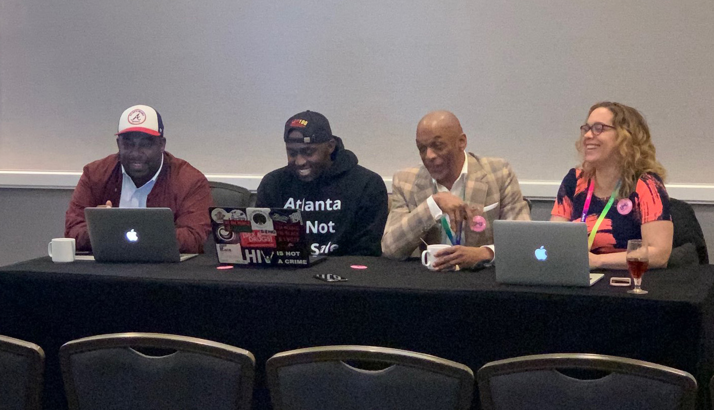 Four people sitting at a table in a conference room.